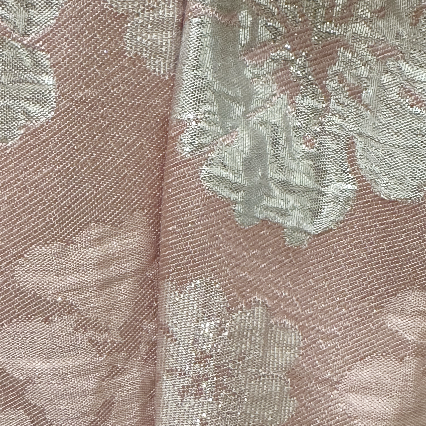 Close-up of a textured fabric with floral pattern in pink and silver.