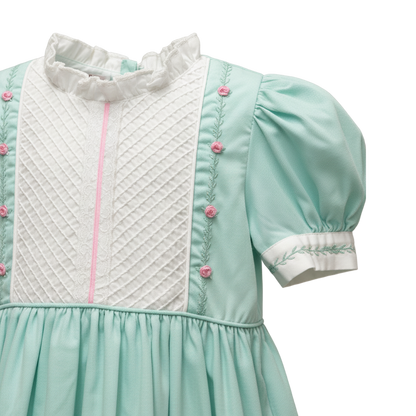 Light teal dress with white quilted panel and pink buttons on a white background